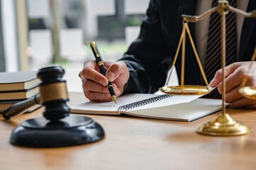 justice and law concept. the judge in a courtroom with the gavel, male judge with writing documents on the table in office, closeup