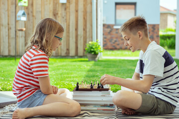 Wall Mural - Happy children playing chess on backyard at sunny day while summer holidays