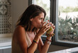 © ADDICTIVE STOCK - Caucasian girl is having a green vegetable juice in front of her big kitchen window.