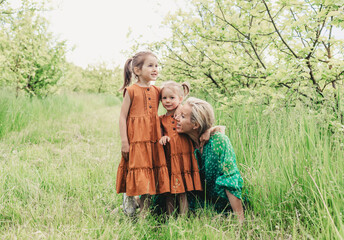 a young mother plays with two young daughters in the spring garden