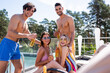 © LIGHTFIELD STUDIOS - Multiethnic friends with beer looking at camera near swimming pool outdoors
