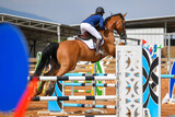 Fototapeta Konie - Rider on horse jumping over a hurdle during the equestrian event	

