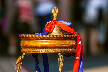 Golden school hand bell with ribbons as symbol of beginning of elementary school education for little children. Close up of ringing schoolbell on table on schoolchildren background.