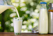 Milk Pouring From Jug Into Glass Outdoors