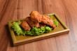 deep fried crispy chicken wings on lettuce and bamboo plate wood table asian snack halal menu fast food cuisine