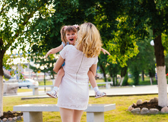 A young woman and her daughter are spinning in their arms. Mom and daughter are laughing and having fun.