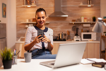 Freelancer woman having a conversation on phone while working from home late at night. Employee using modern technology at midnight doing overtime for job, business, career, network, lifestyle