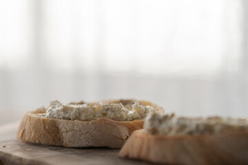 Wall Mural - Ciabatta slices with cream cheese and herbs on olive wood board