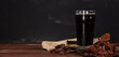 Glass of beer stout standing on wooden board next to chocolate muffin. Horizontally stretched panoramic image for banner