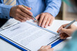 © crizzystudio - Businesswoman signing a document or application form in a folder, Businessmen hand's pointing where to sign a contract, legal papers or application form.