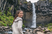 Portrait Of Woman On Iceland. Hiker Enjoying Svartifoss Waterfall. Female Is Visiting Famous Tourist Attraction Of Iceland. Natural Landmark On Vacation In Skaftafell. Icelandic Nature Landscape