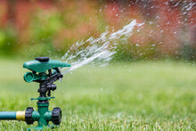 Lawn Sprinkler Watering Grass In Yard. Water Usage, Restrictions And Lawncare Concept