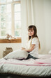 © Marina - happy little girl in pajamas sitting on the bed