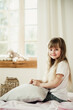 © Marina - little girl sitting on the bed with a pillow