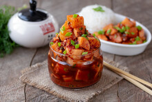 Kkakdugi. Korean Cubed Radish Kimchi In A Glass Jar On Wooden Table. Plate With Cooked Rice And Kimchi On Background.
