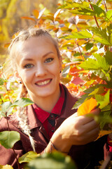 Portrait of a beautiful young woman in an autumn park on a yellow background with leaves