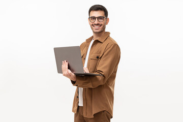 Wall Mural - Young man standing holding laptop and looking at camera with happy smile, isolated on gray background