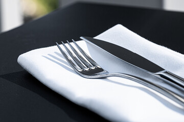 Wall Mural - Fork and knife with white napkin on table in luxury restaurant outdoors, fine dining menu for wedding or event and food catering service concept.