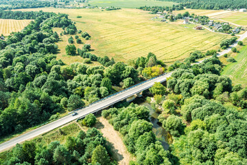 traffic bridge over a small winding river among agricultural fields in the countryside. aerial view