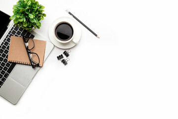 Flat lay, top view office table desk. Workspace with blank Laptop, office supplies, pencil, green leaf, and coffee cup on white background.