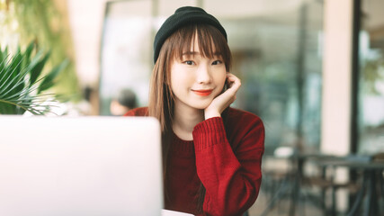 Wall Mural - Young adult asian college student woman with laptop for study at cafe on winter day.