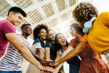 Multiracial happy friends with hands in stack. Multi-ethnic diverse group of college students joining their hands. Stacking hand concept, community, unity and teamwork concept