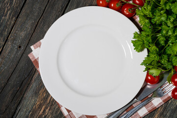 Wall Mural - table setting with white plate and vegetables on wooden background, top view