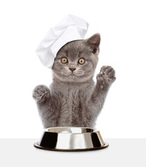 Poster - Kitten wearing chef's hat sits with empty bowl. isolated on white background