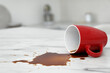 © New Africa - Overturned cup and spilled coffee on white marble table in kitchen, space for text