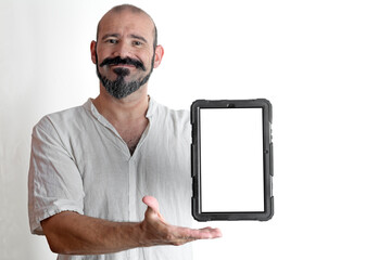 Caucasian smiling man pointing and showing a tablet on a white background, dressed in white
