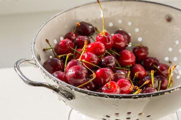 Fresh red ripe organic sweet cherry in the white steel colander. Healthy vegan food.