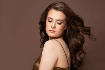 Beautiful fashionable young woman posing in a studio. Long wavy hairstyle and natural nude makeup.