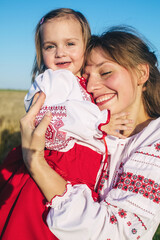 A family in a poppy field dressed in a national Slavic costume. Mom, dad and twin girls in embroidered shirts frolic on sunny day. Concept of a happy childhood, history and togetherness with ancestors