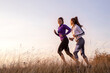 Young and happy best female friends in sportswear jogging together in nature