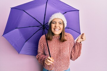 Sticker - Young beautiful woman holding purple umbrella screaming proud, celebrating victory and success very excited with raised arm