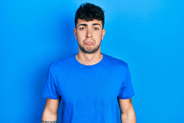 Sticker - Young hispanic man wearing casual blue t shirt depressed and worry for distress, crying angry and afraid. sad expression.