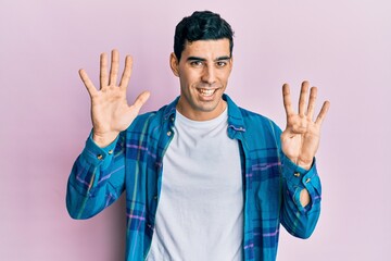 Wall Mural - Handsome hispanic man wearing casual clothes showing and pointing up with fingers number nine while smiling confident and happy.