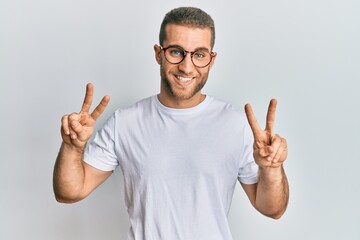 Wall Mural - Young caucasian man wearing casual clothes and glasses smiling looking to the camera showing fingers doing victory sign. number two.