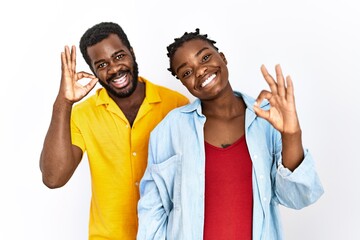 Canvas Print - Young african american couple wearing casual clothes smiling positive doing ok sign with hand and fingers. successful expression.