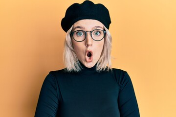 Poster - Young blonde girl wearing french look with beret afraid and shocked with surprise expression, fear and excited face.