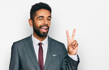 Wall Mural - Young african american man wearing business clothes smiling with happy face winking at the camera doing victory sign. number two.