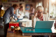 © luckybusiness - An elderly female office employee is focused on a work on laptop