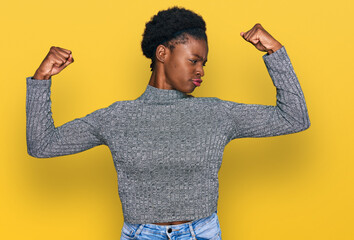 Sticker - Young african american girl wearing casual clothes showing arms muscles smiling proud. fitness concept.