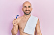 Young bald man shirtless holding razor looking positive and happy standing and smiling with a confident smile showing teeth