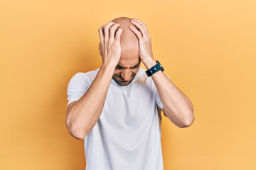 Poster - Young bald man wearing casual white t shirt suffering from headache desperate and stressed because pain and migraine. hands on head.