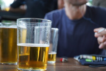 A young man with a cigarette in his hand and a few glasses of beer in front of him