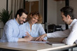 © fizkes - Happy young couple signing contract at meeting with manger realtor or broker in office, excited family closing insurance or investment deal, husband in glasses putting signature on document