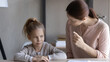 Child and parent conflict. Strict mother scolding lecturing stubborn preteen girl daughter sitting at desk reprimanding for bad behavior promise punishment. Angry mom rebuking idle kid for laziness