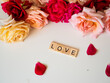 LOVE - napis z drewnianych kostek, róże w tle, różowy kolor