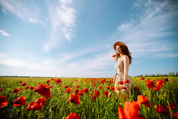 Beautiful woman in a blooming poppy field. People, lifestyle, travel, nature and vacations concept.